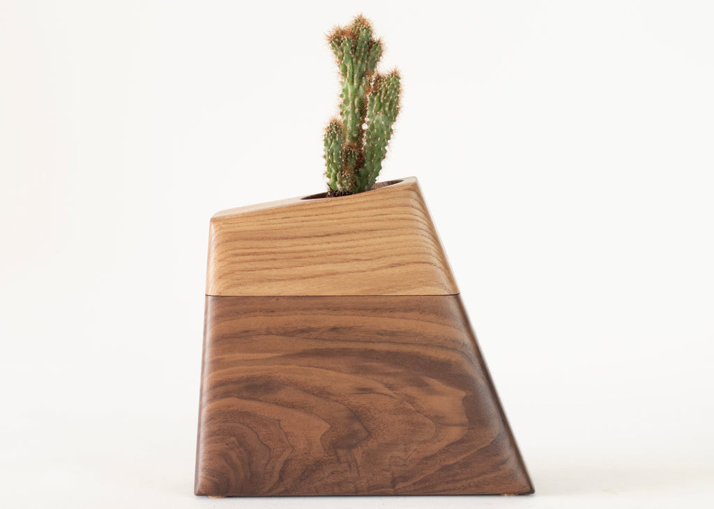 Handmade modern cremation urn for pets crafted from rescued California Elm and FSC-certified Black Walnut. It features a sculptural, geometric design with a recessed plant holder on top and a secure lower compartment for ashes, sealed with hidden magnets.